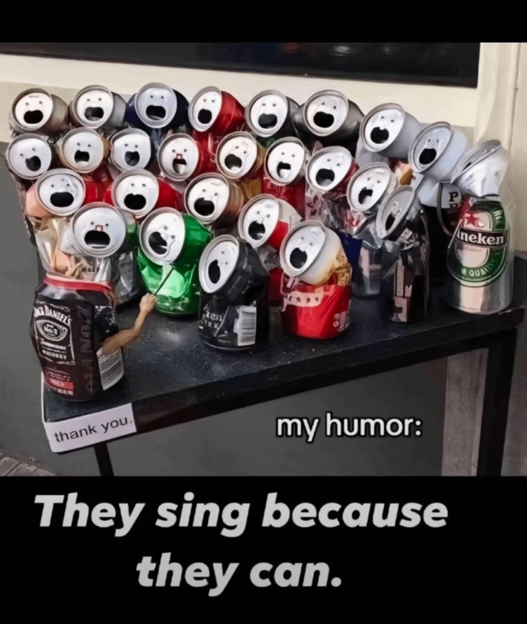 A collection of crushed aluminum cans with faces drawn on them, mimicking a choir singing. A Jack Daniel's can with a drawn arm conducts the group. Text reads, "They sing because they can.
