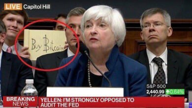 A man holds a "Buy Bitcoin" sign during a Federal Reserve hearing. The image captures a bold act, drawing attention to Bitcoin and cryptocurrency during Janet Yellen's testimony at a House committee.