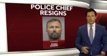 News anchor in a blue suit reports on Bethel, Ohio Police Chief Chad Essert's resignation following a 70-count sexual misconduct indictment, with Essert's mugshot displayed on a red screen with "POLICE CHIEF RESIGNS" text.
