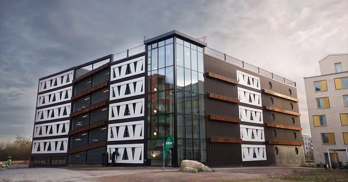 The Niels Bohr car park in Lund, Sweden, showcases innovative architecture using recycled wind turbine blades as cladding. Its façade features geometric blade panels alongside a modern glass elevator tower.