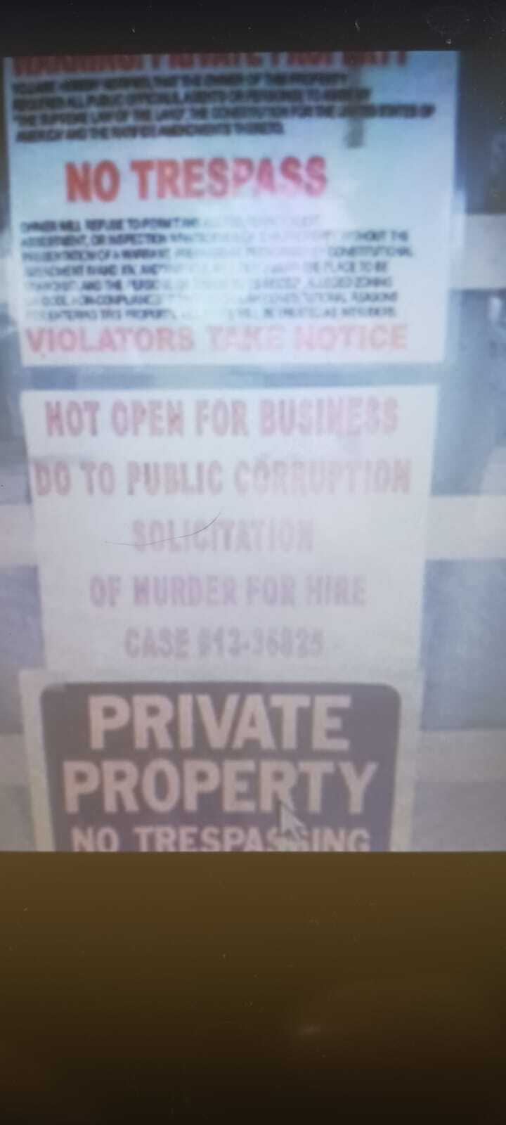 Signs posted on private property in North Fort Myers, Florida, warn against trespassing and state the property is "Not Open for Business" due to alleged "Public Corruption" and "Solicitation of Murder for Hire." A "No Trespassing" sign is also visible. This image may be related to the Enzo Vincenzi case involving false arrest and claims of police misconduct by Lee County deputies.