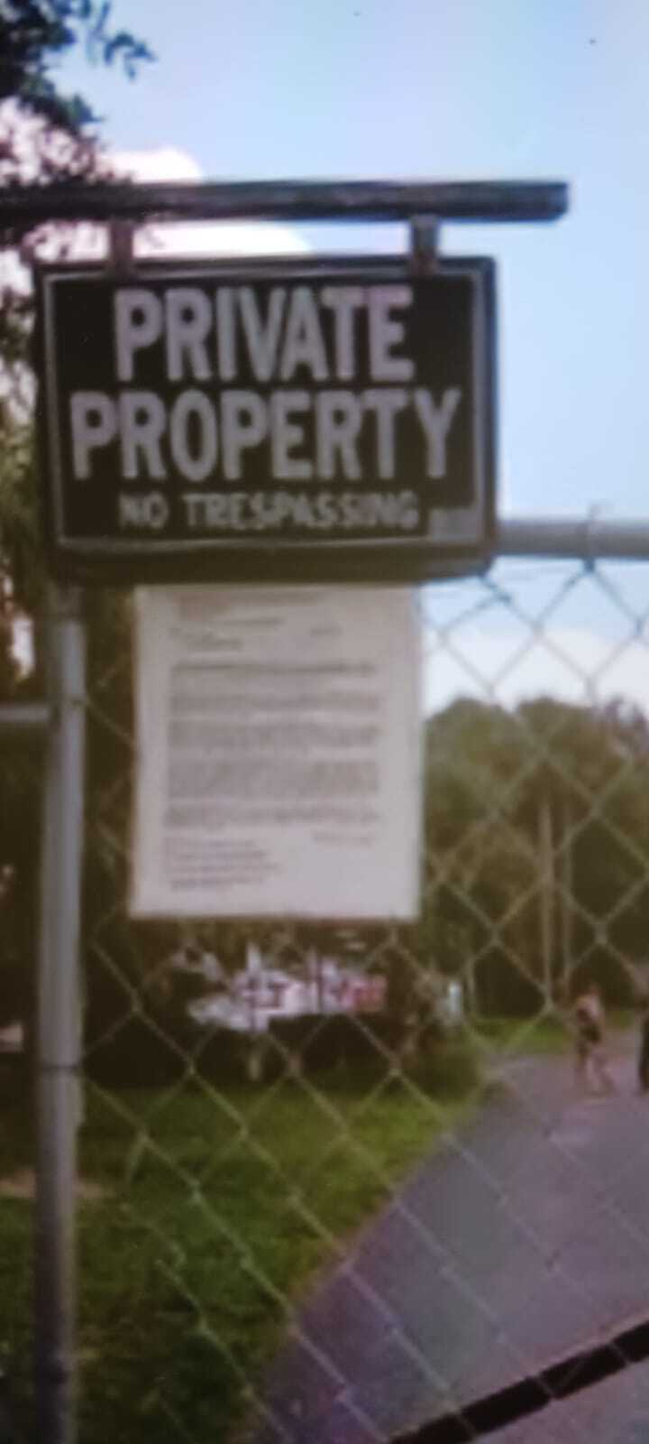 A "Private Property, No Trespassing" sign hangs on a chain-link fence, indicating a private area. This image relates to the case of Enzo Vincenzi, highlighting a possible "False arrest on private property" scenario in North Fort Myers, Florida.