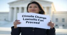 A woman holds a sign reading "Climate Change Lawsuits Can Proceed" in front of the Supreme Court building. The image highlights the Supreme Court's ruling allowing lawsuits against oil companies to proceed, a key step in climate action.