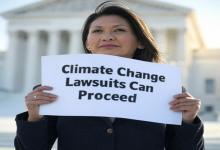 Supreme Court Allows Climate Change Lawsuits Against Oil and Gas Companies to Proceed woman holding up a sign at the US supreme court