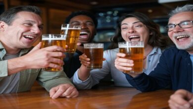 Yes, your beer tastes better ice cold, and scientists discovered why Four friends are gathered at a lively bar, each holding a glass pint of beer. Their glasses are raised in the air for a toast, and as they clink their glasses together, some beer splashes out, adding to the jovial atmosphere. They're all smiling, caught in a moment of camaraderie and celebration