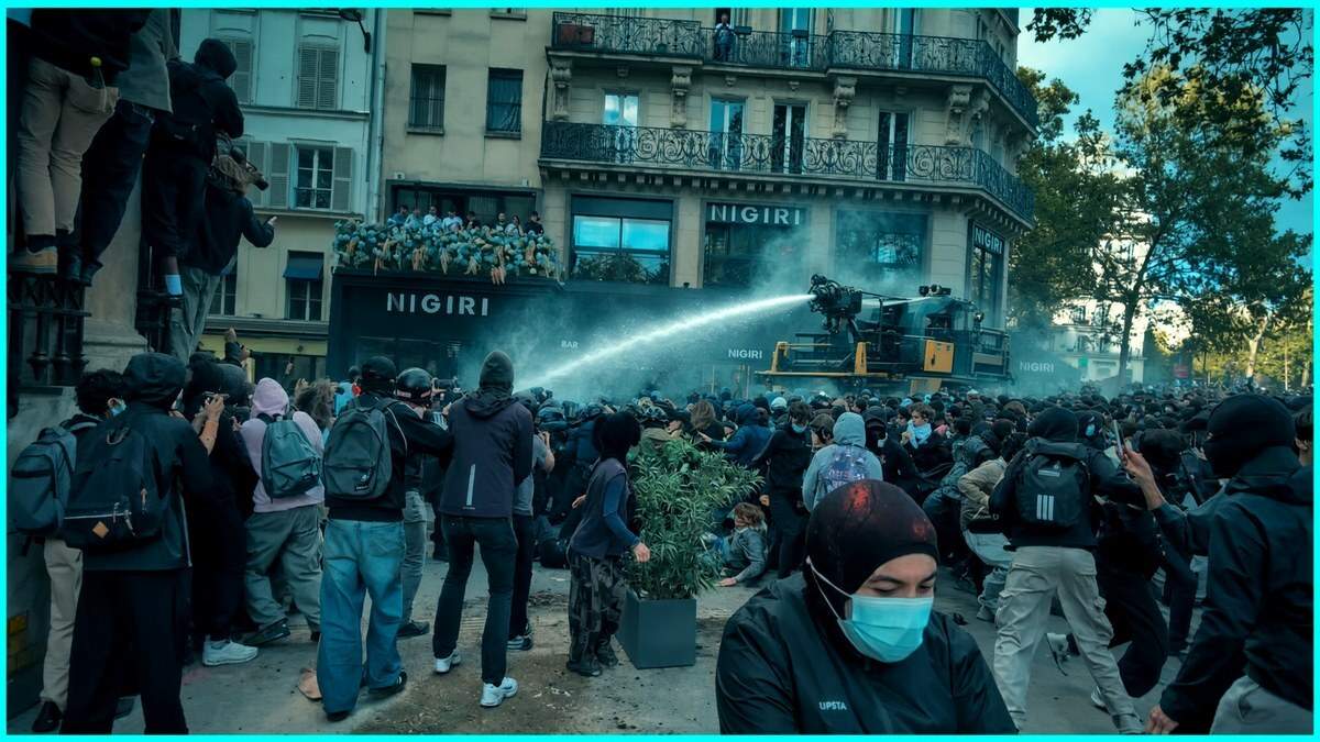 Screenshot of a water cannon spraying student protesters at Place de la Bastille in Paris, with a teal border and an on-screen French caption