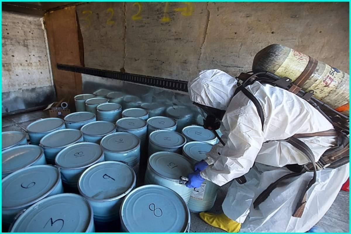 A hazmat investigator checks rows of chemical drums during a cyanide seizure tied to illegal gold mining
