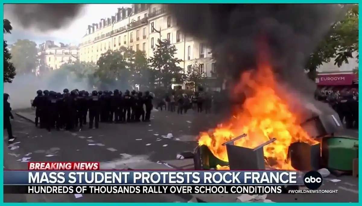 Screenshot of riot police beside a burning barricade during mass student protests in France over school conditions