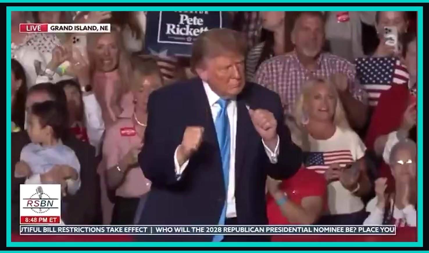 Donald Trump doing the Trump YMCA dance on stage in Grand Island, Nebraska, with a Pete Ricketts sign behind him